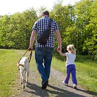 Father and a young daughter and a seeing eye dog walking away