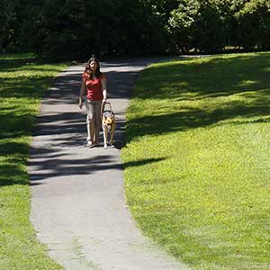 visually impaired woman walking in a park with her seeing eye dog